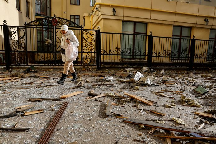 A woman walks past glass and debris in the street after an overnight attack in Donetsk.