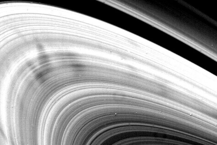 What causes dark spots in Saturn's rings?